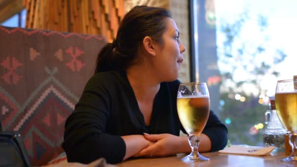 Una ragazza sta bevendo birra da un bicchiere. La birra in un bicchiere e 'sul tavolo. Un pub di birra è un ristorante
. - Filmati, video