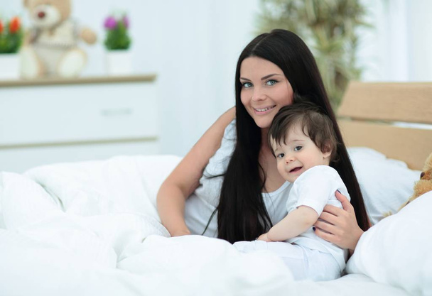 Retrato de una hermosa madre con su bebé en el dormitorio
 - Foto, imagen