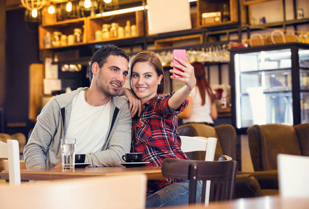 couple taking self portrait in coffee shop - Photo, Image