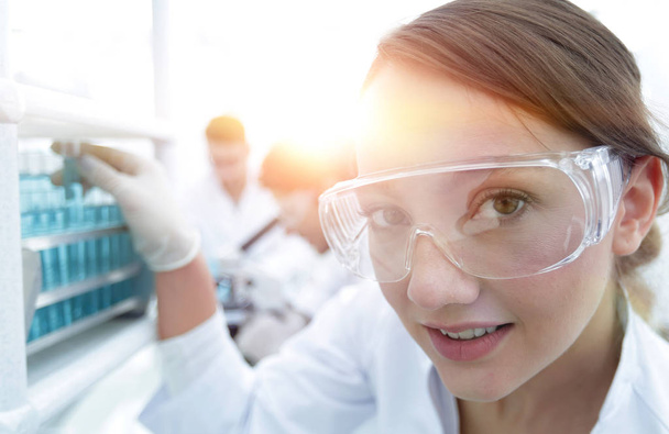 Young woman scientist in protective glasses holding test tubes - Photo, image