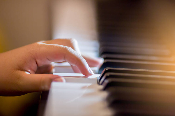 Selectieve aandacht van kind vingers en piano sleutel tot het spelen van de piano met verlichting. Er zijn muziekinstrument voor concert of leren muziek. - Foto, afbeelding