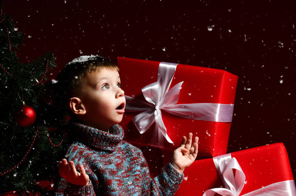 little boy on the eve of new year and christmas is sitting under the tree - Photo, image