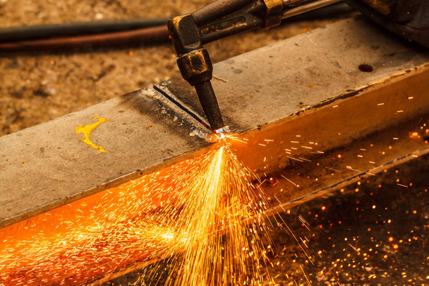 Soudeur dans la construction métallique de fabrication d'atelier en coupant à la forme à l'aide d'énormes étincelles orange
 - Photo, image