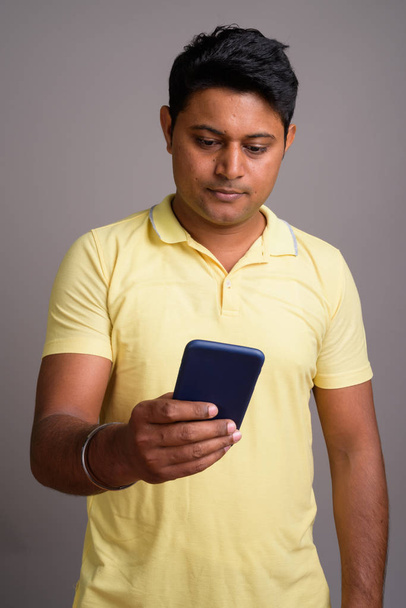 Portrait of young Indian man against gray background - Foto, Imagem