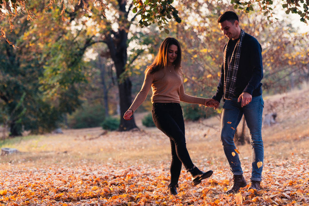 Couple kicking leaves feeling happy and joyful. - Photo, Image