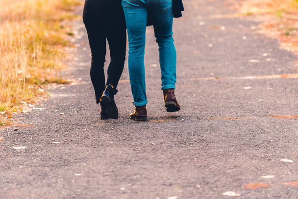 ブーツとジーンズ、公園で歩くカップル. - 写真・画像