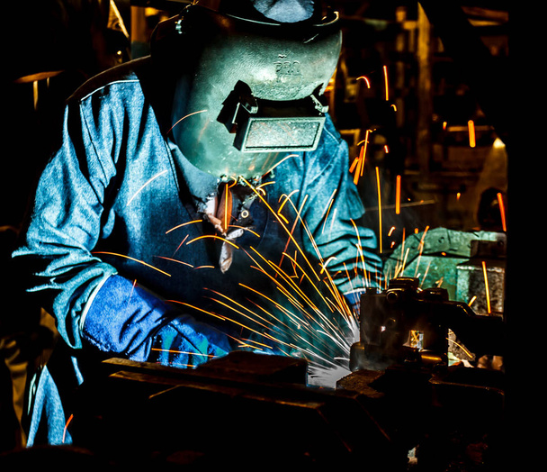 Soudeur travaillant un métal de soudage avec masque de protection et étincelles
 - Photo, image