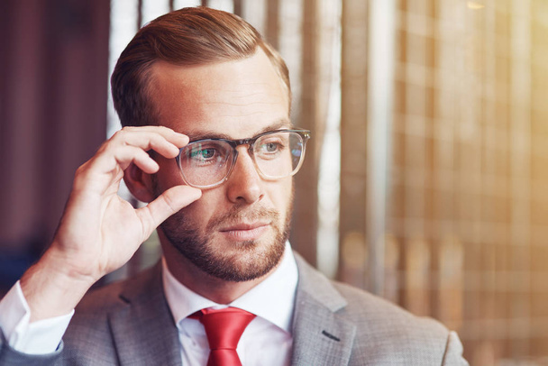 Zelfverzekerde en stijlvolle. Portret van een professionele knappe zakenman holding zijn bril en kijken terwijl je op kantoor - Foto, afbeelding