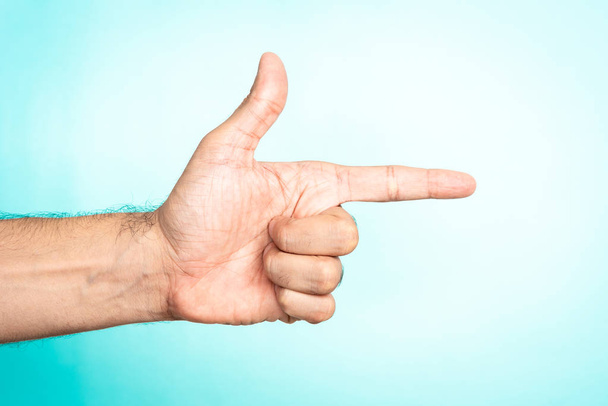 Thumb up and index finger making gun on blue background. Social media as weapon, Guerrilla marketing concept. - Photo, Image
