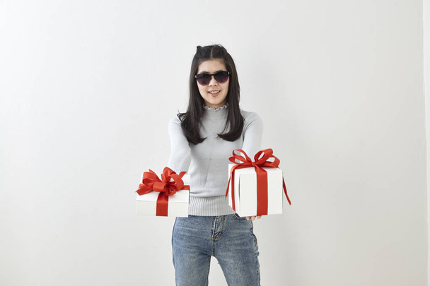 Giovane donna asiatica mostra OK con una scatola regalo su sfondo luminoso muro grigio
 - Foto, immagini