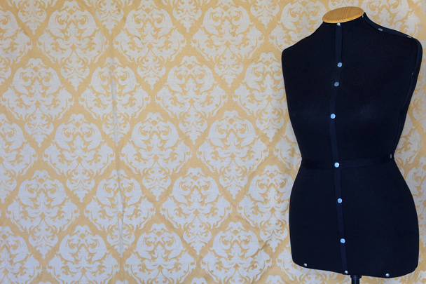 Female mannequin for tailoring. Wallpaper with pattern in the background. - 写真・画像