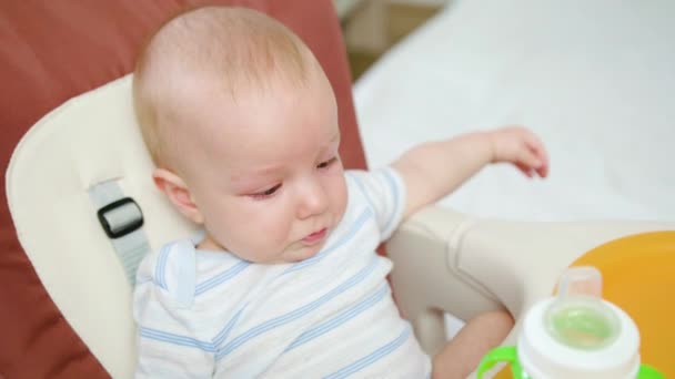 Bebé lindo bebiendo en la silla en casa
 - Imágenes, Vídeo
