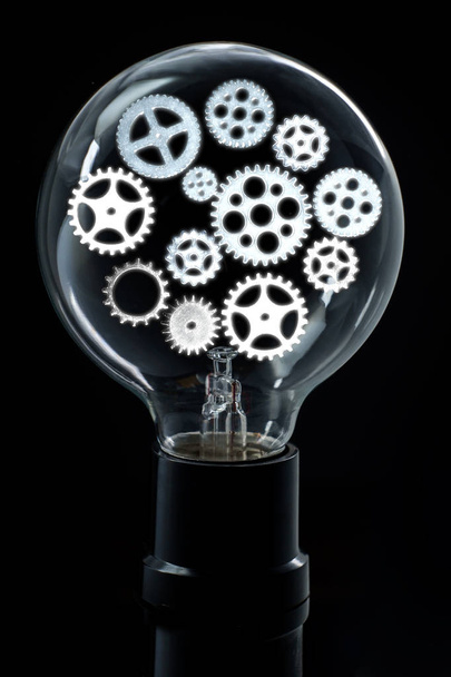 Light bulb with bright gears and cogs for brainstorming ideas concept - Photo, Image