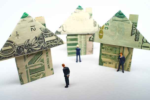 Миниатюрные фигурки бизнесменов и оригами бумажные денежные дома для концепции рынка недвижимости и жилья - Фото, изображение