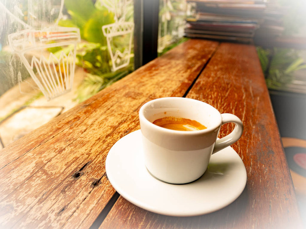 Espressokoffie, kopje koffie op houten tafel. Traditionele, warmte. Kopje espresso koffie op houten tafel in een café - Foto, afbeelding