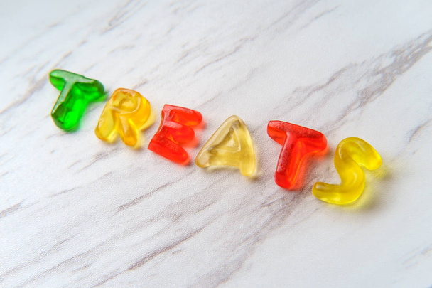 Diverse kleurrijke gummy-snoep brieven spellen het woord traktaties - Foto, afbeelding
