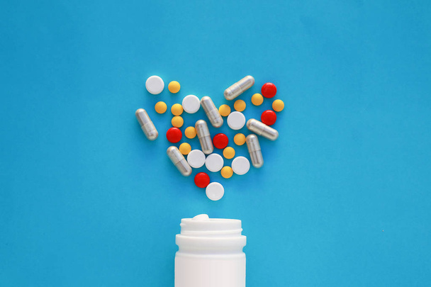 Таблетки серце з пляшки таблеток на синьому фоні, вид зверху
 - Фото, зображення