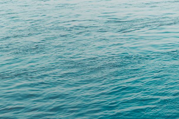 Vista della superficie dell'acqua blu fluente Clean con increspature e raggi solari o riflessi di luce solare. Bella acqua del mare Adriatico brilla alla luce del crepuscolo. Bellezza naturale Onda disegno texture acqua per lo sfondo
. - Foto, immagini