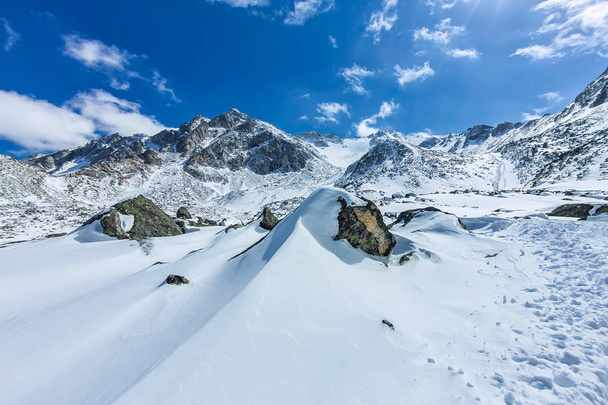 View from the valley to the top of the snowy mountains under the blue sky - Foto, afbeelding
