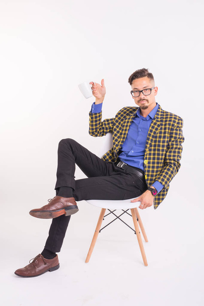 Business and people concept - Handsome man sits in his chair and holding a cup on white background - Fotografie, Obrázek