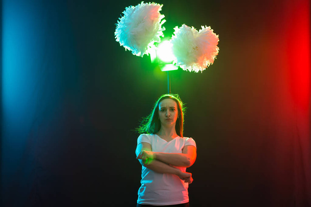 Вболівальник молода жінка танцює з помпонами на барвистому фоні
 - Фото, зображення