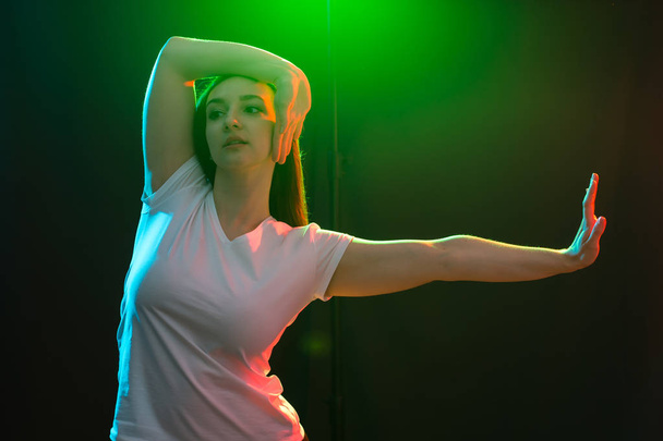 Ludzie, jazz, funk i koncepcja tańca - młoda kobieta tańczy w ciemności i posiada jedną ręką w pobliżu jej twarz - Zdjęcie, obraz