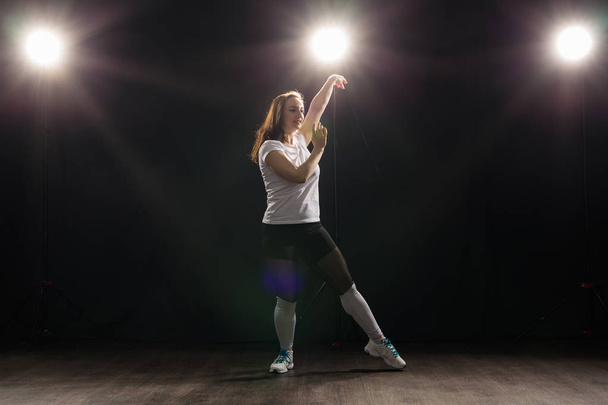 Koncepcja ludzie i taniec - młoda kobieta taniec jazz funk na ciemnym tle - Zdjęcie, obraz