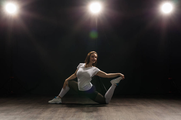 Młoda kobieta tancerz gimnastyka ćwiczenia pozie na ciemnym tle - Zdjęcie, obraz