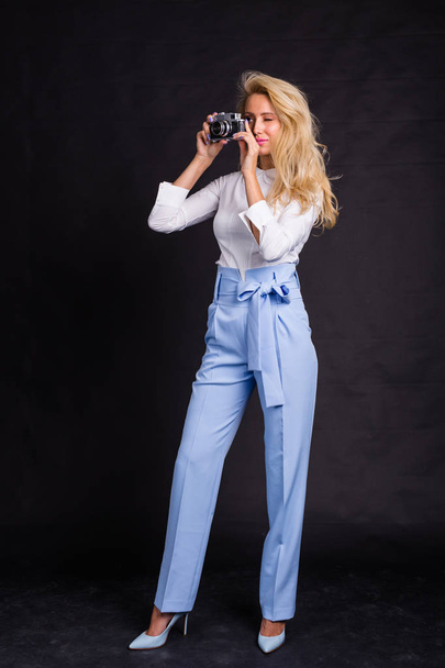 Leisure, fashion and people concept - young blonde female photographer taking a photo from something and watching through the camera - Photo, Image