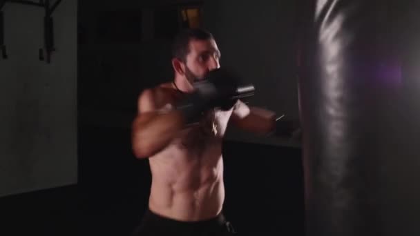 Man boxer making strikes on a boxing bag. Fighter training indoor - Footage, Video