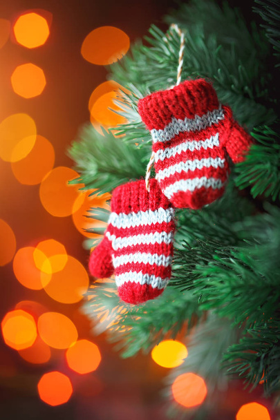 Merry Christmas and happy New year. Small knitted mittens on the Christmas tree. Background with copy space. - Photo, Image