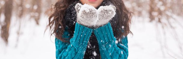 Noël, vacances et concept de saison - Gros plan de jeune femme brune heureuse soufflant de la neige en hiver nature
 - Photo, image