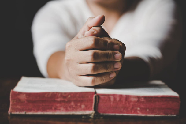 Mani di donna che pregano con una bibbia in un tavolo di legno scuro
 - Foto, immagini