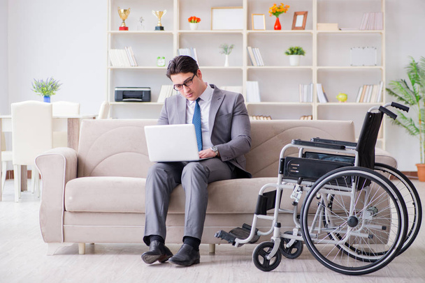Деловой человек на инвалидной коляске работает дома - Фото, изображение