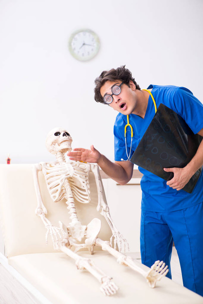 Funny doctor with skeleton in hospital - Фото, изображение