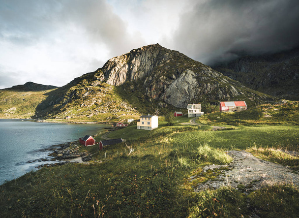 Traditional red fishin house in Bjoernsand near Reine in Lofoten, Norway with red rorbu houses. Sunset afternoon with clouds on a sandy beach. - Foto, immagini