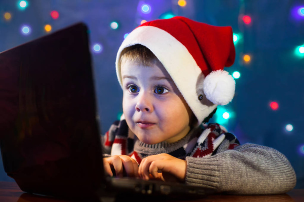 Niño pequeño escribiendo carta a Santa Claus en el ordenador portátil. Vacaciones de invierno Navidad y Año Nuevo concepto
. - Foto, imagen