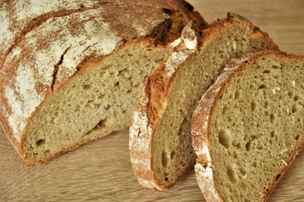 Baked wheat bread, half and two slices of sliced - Photo, Image