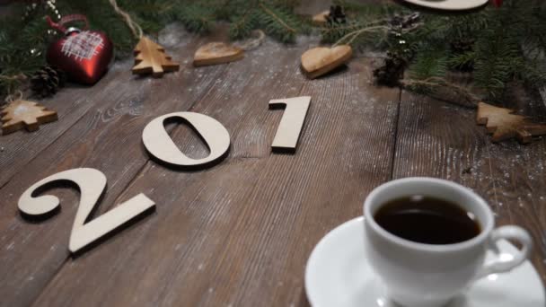 Feliz Navidad y feliz año nuevo concepto. Los símbolos del año Ney se ponen sobre un fondo de madera junto con una taza de café. La mano femenina pone símbolos numéricos 2019. Tarjeta postal de vídeo. hd
 - Metraje, vídeo