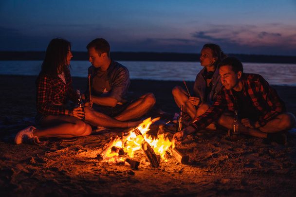 young friends have picnic with bonfire on the beach - 写真・画像