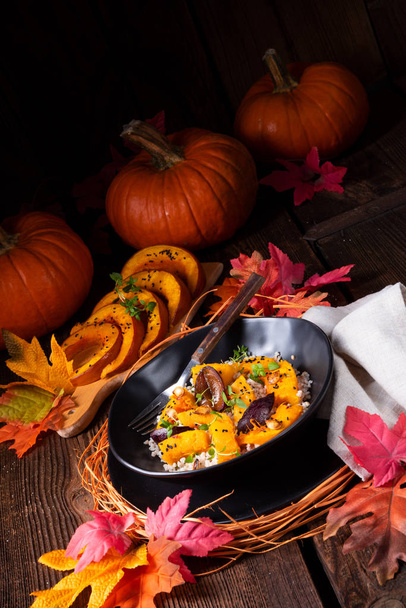 тарелка с вегетарианской тыквой с ячменной крупой и сливами с тимьяном и осенними листьями на заднем плане
  - Фото, изображение