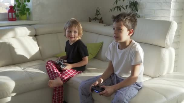 Two kids emotionally playing videogames at home at sunny morning - Záběry, video
