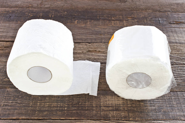 Toilet paper rolls packed in cellophane on wooden background - Photo, Image