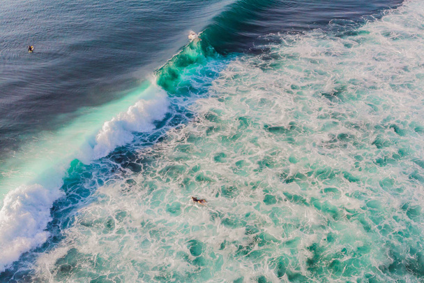 Aerial view of people surfing on waves in ocean water at tropical resort. - Foto, afbeelding