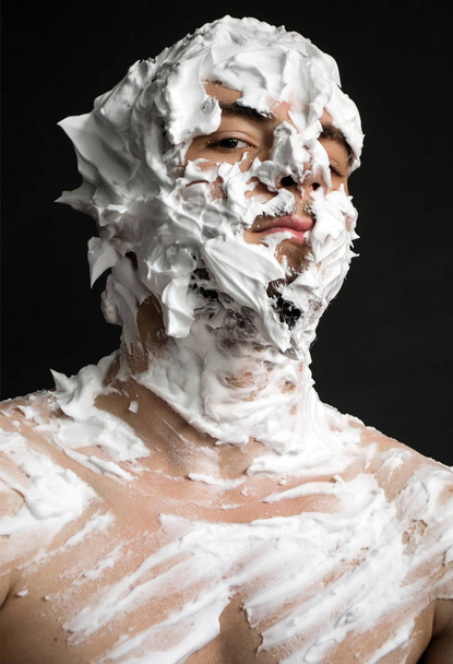 portrait of a young man smeared all over his face shaving foam - Photo, Image