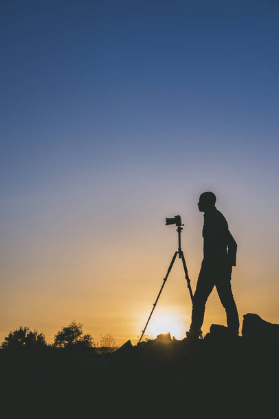 Silhouette di fotografo nero che scatta foto al tramonto. Immagine con spazio di copia
. - Foto, immagini