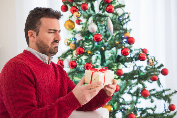Disappointed man receiving small present for christmas - Photo, Image