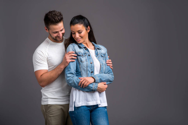 A beautiful young couple hugging and holding each other in the studio - Фото, изображение