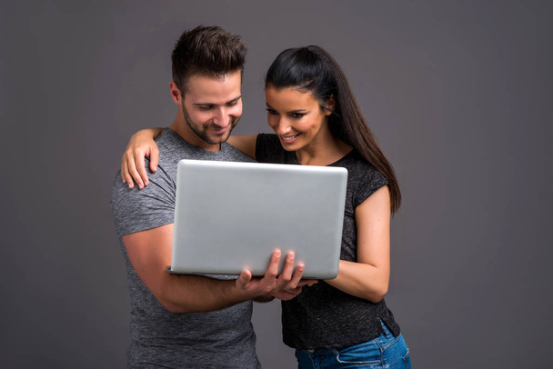 A beautiful young couple looking at a laptop and smiling - Foto, Imagem