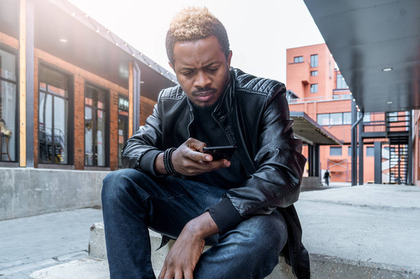 Крупним планом темношкірий чоловік дивиться на екран мобільного телефону
. - Фото, зображення